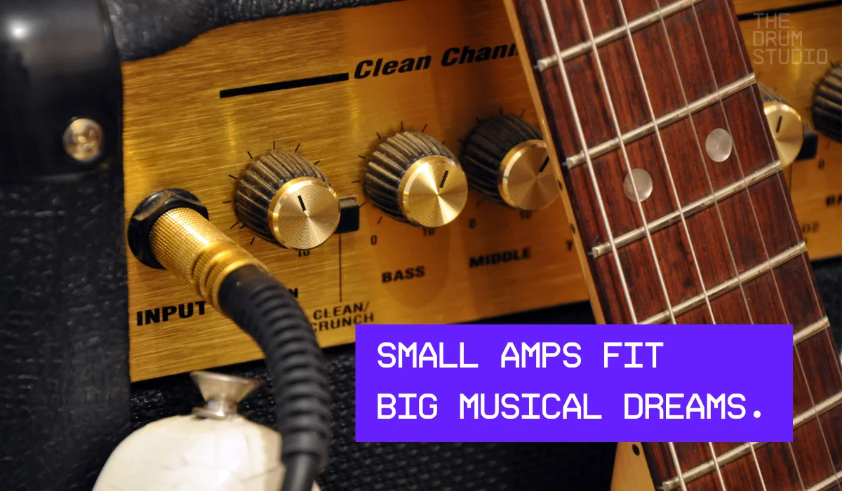 Close-up of small amp with guitar and gold tone knobs.