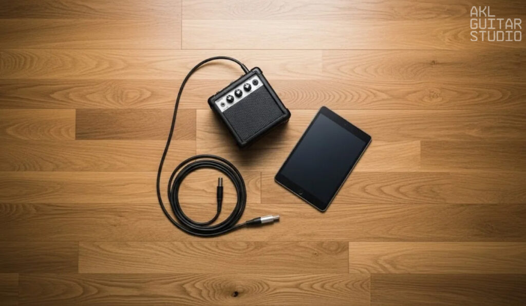 Small amp, tablet, and cable placed neatly on wooden floor.