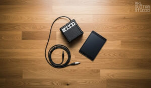 Small amp, tablet, and cable placed neatly on wooden floor.