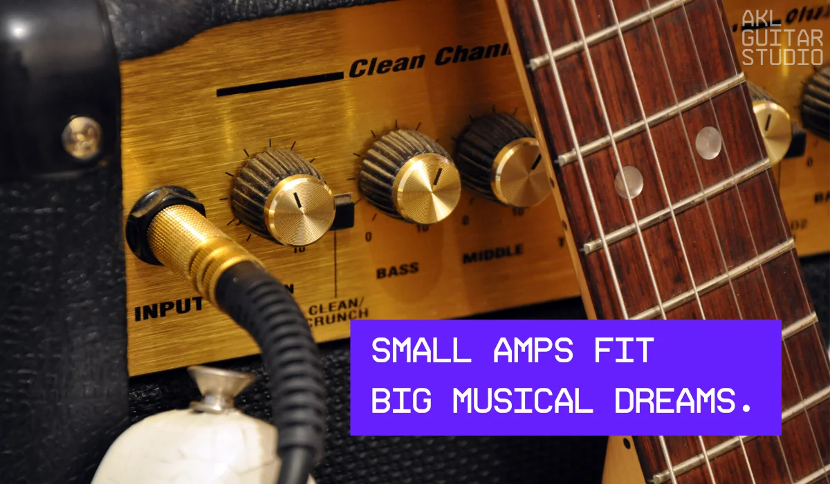 Close-up of small amp with guitar and gold tone knobs.